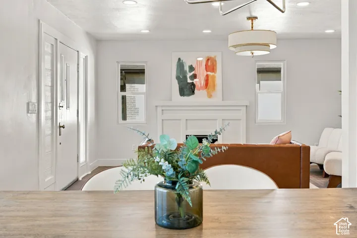 Fireplace with a custom mantel, multi-tiered drum chandelier, recessed lighting, and white exterior-style entry door