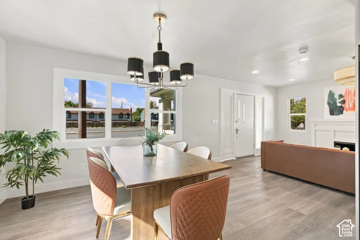 Open-concept interior featuring wood-finish flooring, a multi-light drum chandelier, recessed lighting, and a white fireplace mantel