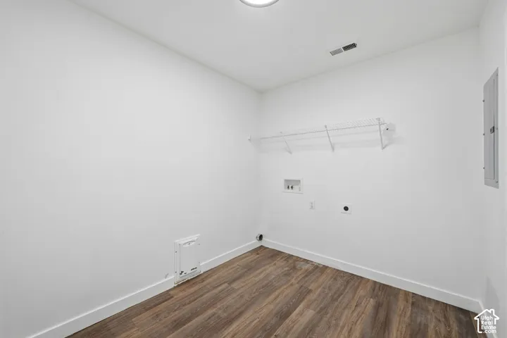 Utility space featuring wood-finish flooring, white walls, wall-mounted wire shelving, and dedicated washer and dryer hookups