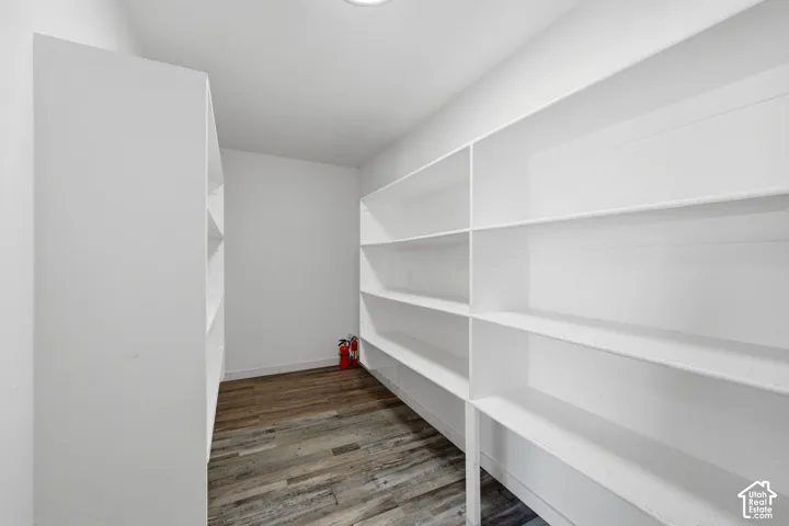 Custom walk-in storage featuring extensive built-in white shelving and wood-finish flooring
