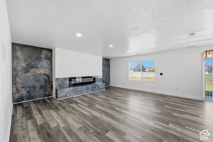 Interior space featuring wood-finish flooring, recessed lighting, and a floor-to-ceiling fireplace surround with horizontal shiplap detailing and a linear electric insert