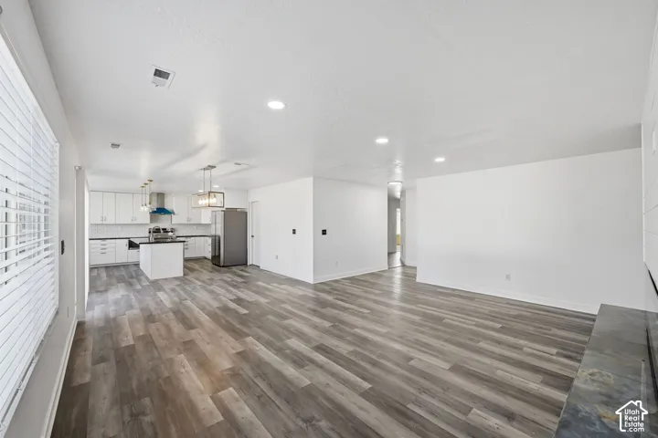 Open interior featuring wood-finish flooring, recessed lighting, white cabinetry, a center island with a dark countertop, and a dark stone hearth