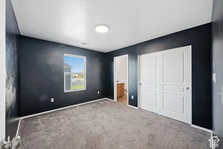 Interior room featuring gray carpeting, dual-panel sliding closet doors, and a single window with blinds