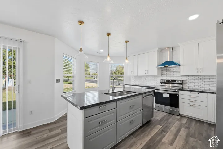 Kitchen featuring a central island with a dark stone countertop, white cabinetry, a white subway tile backsplash, stainless steel appliances, and wood-finish flooring