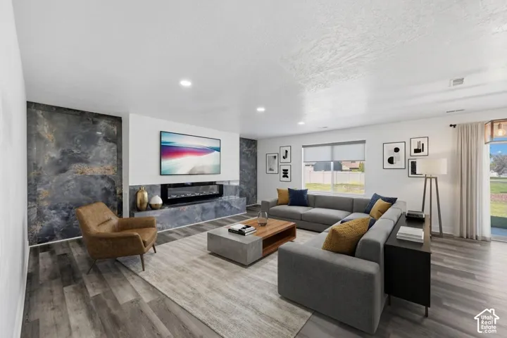 Living area featuring wood-finish flooring, recessed lighting, and a focal wall with white shiplap paneling and large-format dark stone-finish tile surrounding a built-in linear electric fireplace