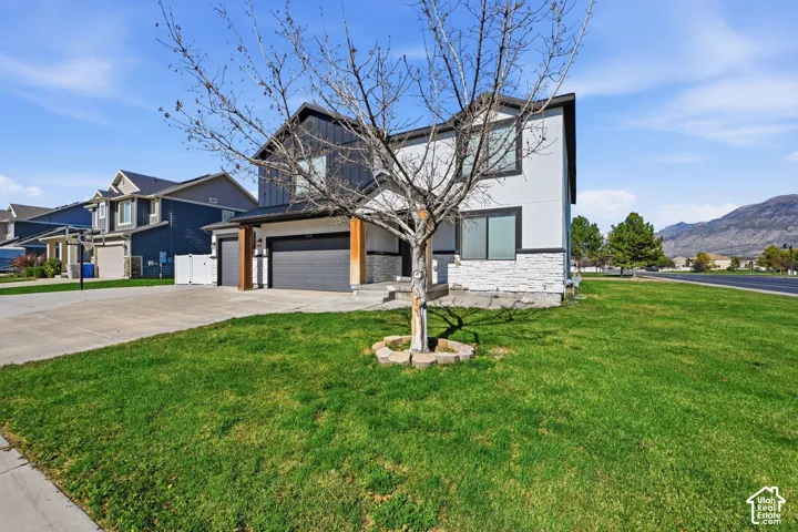 Two-story exterior featuring a mix of vertical metal siding and stucco, stacked stone veneer accents, wood-tone columns, and a multi-car garage