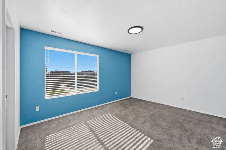 Room featuring grey wall-to-wall carpeting, a large sliding window with horizontal blinds, and a modern circular flush-mount ceiling light