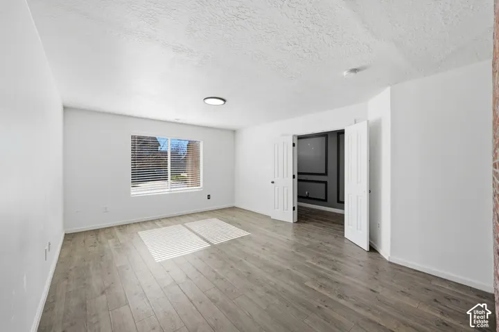 Interior room featuring wood-finish flooring, a double-door entrance, and a window with integrated blinds