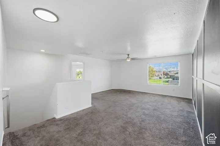 Open-concept interior space featuring grey carpeting, recessed lighting, a ceiling fan, and decorative wall paneling