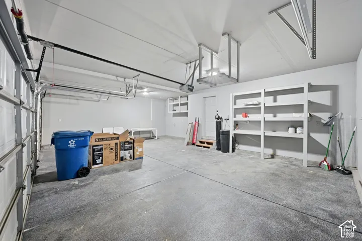 Multi-car garage featuring a concrete floor, built-in wooden shelving, and an automatic door opener