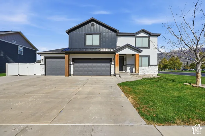 Two-story residence featuring a combination of smooth stucco and vertical panel siding, stone veneer accents, a three-car garage, and natural wood support columns
