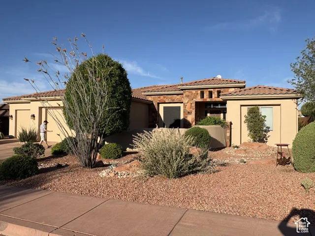 Single-story exterior featuring a stone-veneer facade, tile roof, stucco finish, and xeriscaped front yard