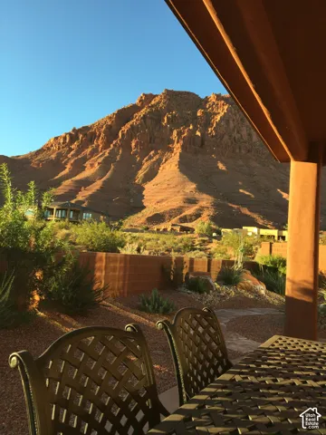 Covered patio featuring a smooth stucco-finished support column, masonry perimeter wall, desert landscaping, and mountain scenery