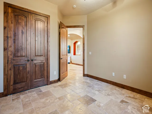 Natural stone flooring with earth-tone variations, stained solid wood double-panel doors, and matching wood trim casing