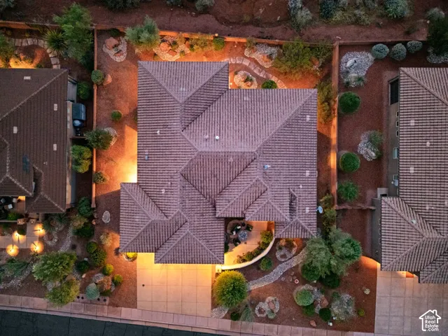 Aerial perspective featuring a multi-gabled tiled roof, a covered patio, and desert-style xeriscaping with stone paths and mature plantings
