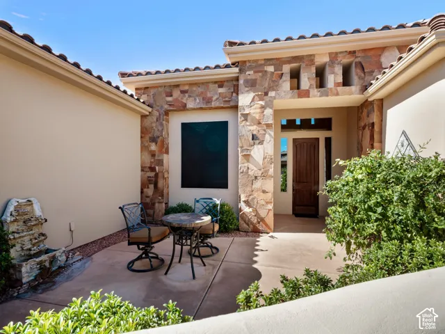 Courtyard MAIN entrance featuring natural stone veneer, concrete patio, recessed entryway, and a wood-panel door