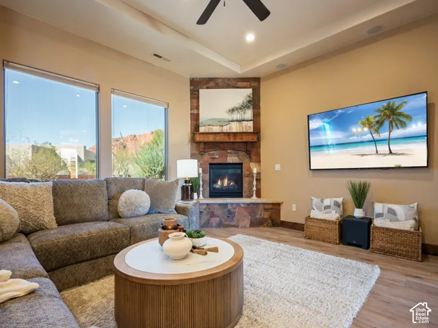 Corner fireplace featuring stacked stone masonry, a built-in hearth, and a timber mantel, complemented by expansive windows, recessed lighting, and speakers