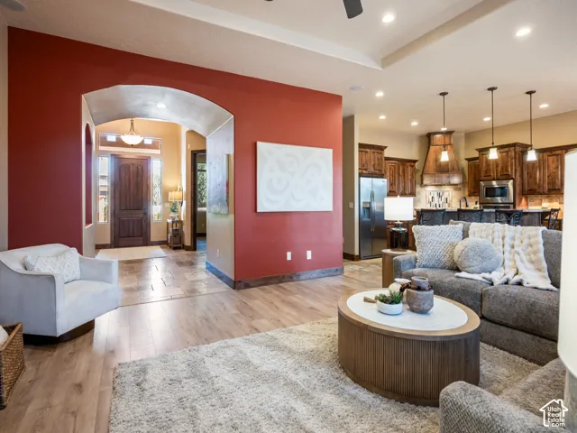 Open floor plan featuring wood-finish flooring, recessed lighting, arched entryway, and kitchen with stained wood cabinetry and stainless steel appliances
