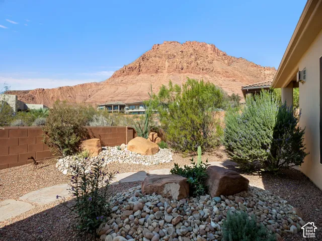 Low-maintenance desert landscaping featuring decorative stone ground cover, native shrubs, large decorative boulders, and mountain backdrop