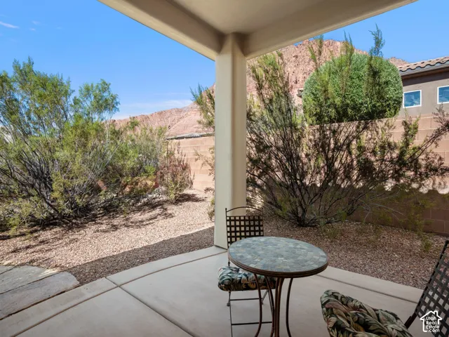 Covered concrete patio featuring rock landscaping, privacy block wall, and desert mountain backdrop