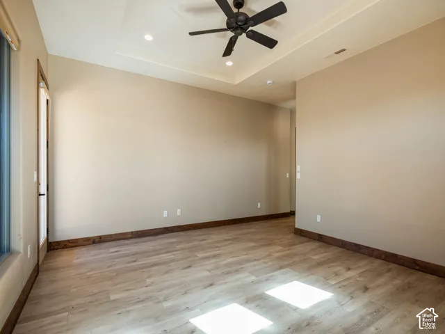 Room featuring wood-finish flooring, tray ceiling, recessed lighting, and a ceiling fan