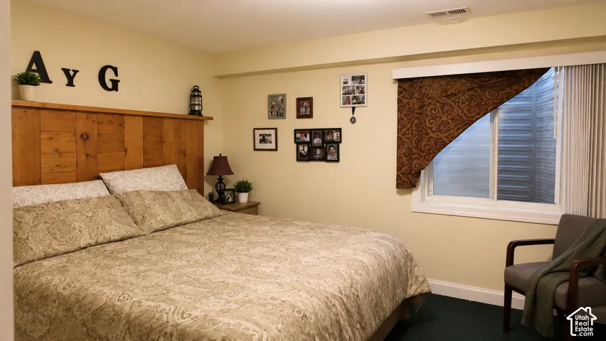 Built-in wooden headboard with integrated shelving, sliding window with corrugated steel window well, and dark carpeting