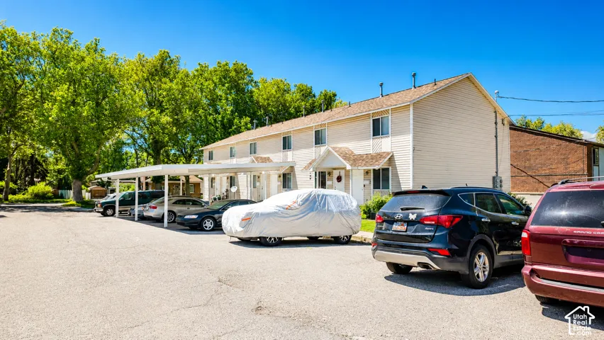 Two-story multi-unit exterior featuring vinyl siding, gable roofline details, and integrated carport parking