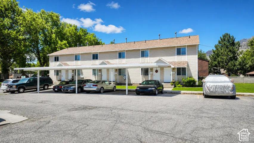 Multi-unit exterior featuring horizontal siding, asphalt shingle roofing, and covered parking structures