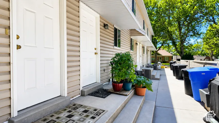 Exterior featuring light-toned horizontal siding, multi-panel entry doors, concrete steps, and recessed wall-mounted lighting