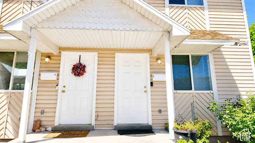 Exterior featuring horizontal siding, decorative diagonal trim accents, covered entryway with a gabled roofline, and wall-mounted exterior lighting