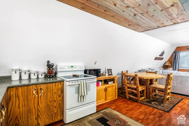 Sloped ceiling with natural wood-plank finish, wood-finish flooring, and custom cabinetry with antler-style hardware