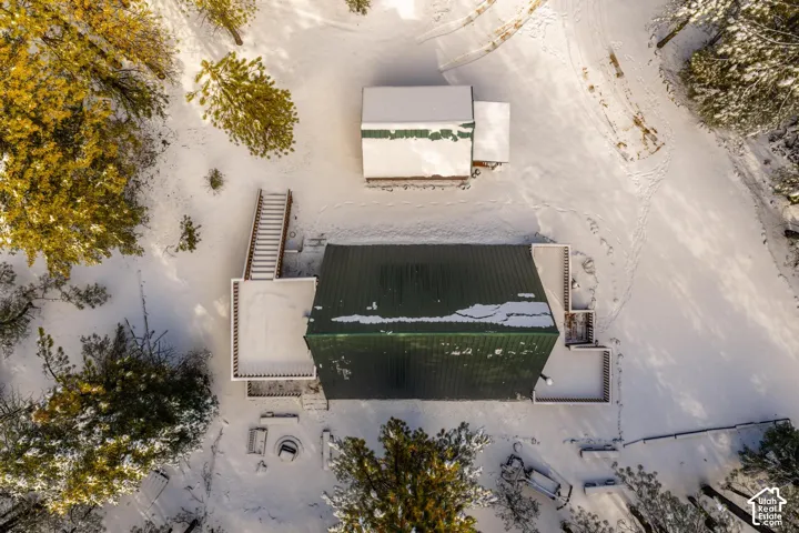 Aerial perspective of a detached residential structure featuring a green metal roof, multiple wrap-around deck levels, exterior staircases, and a separate secondary detached building