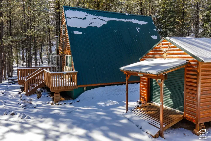 A-frame cabin exterior featuring log siding, a metal roof, and an attached wood deck