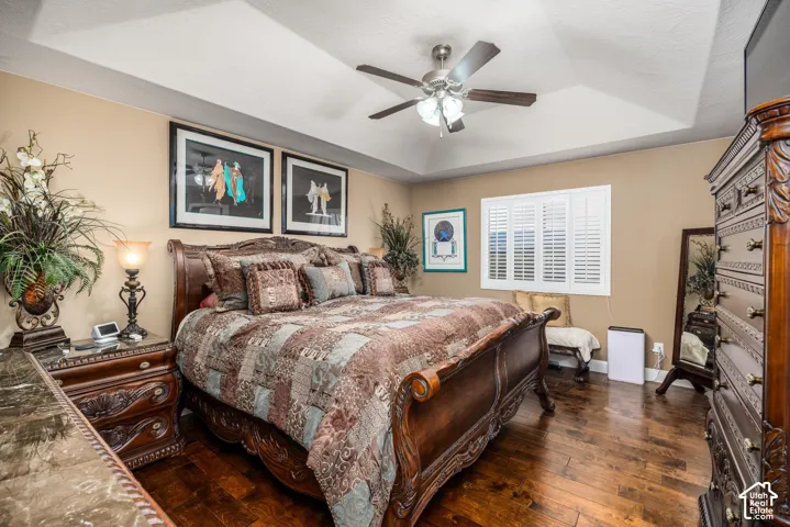 Tray ceiling with recessed lighting, wood-finish flooring, and plantation shutters