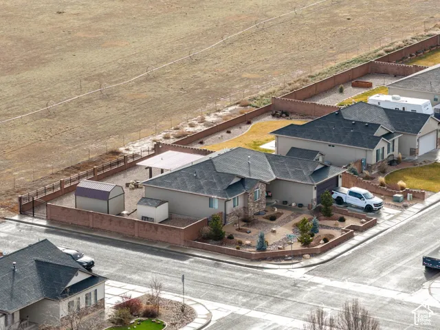 Corner lot featuring an expansive backyard enclosed by a perimeter masonry wall, xeriscaped front grounds, detached storage structures, and a covered outdoor patio area