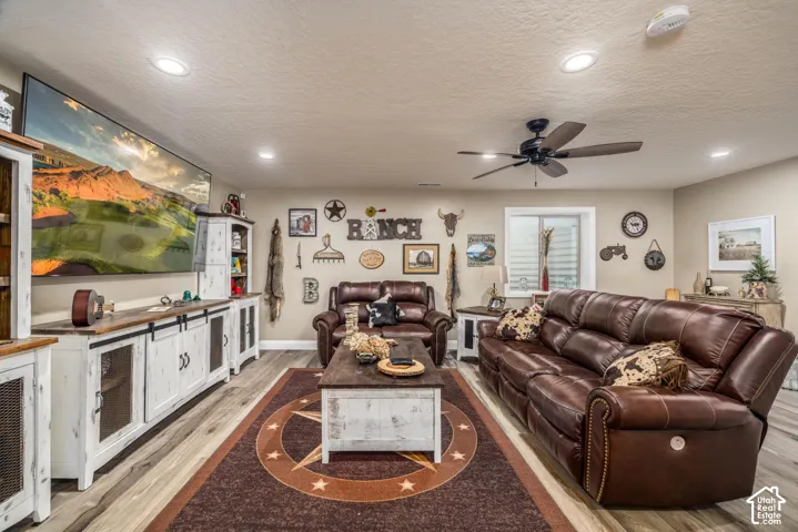 Living area featuring wood-finish flooring, recessed lighting, a ceiling fan, and built-in cabinetry with sliding barn-style doors