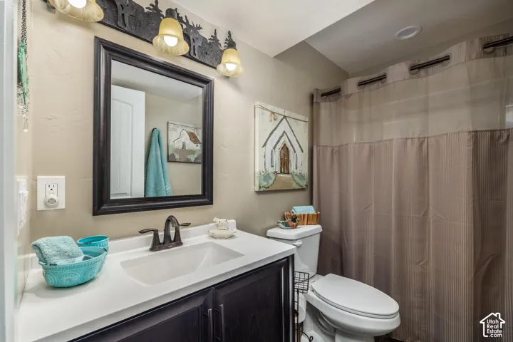 Bathroom featuring a vanity with a white countertop and integrated sink, dark wood-finish cabinetry, a framed wall mirror, and a decorative metal light fixture