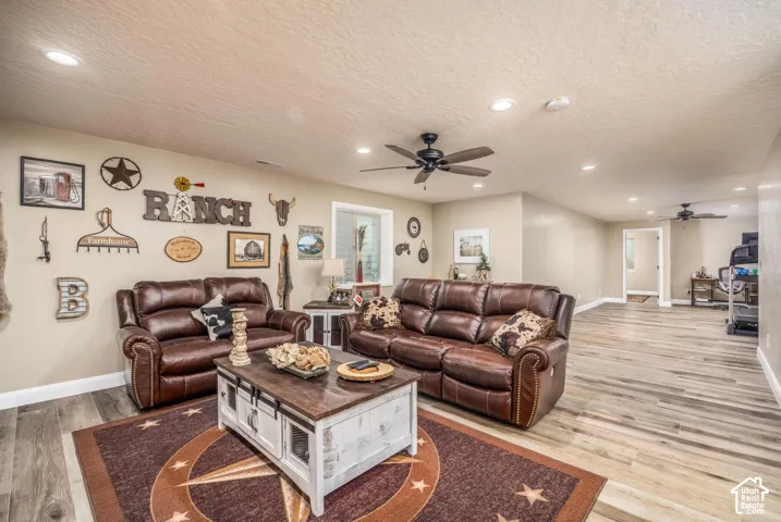 Neutral-toned interior space featuring wood-finish flooring, recessed lighting, and dual ceiling fans