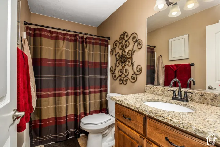 Bathroom vanity featuring a natural stone-finish countertop, undermount sink, oil-rubbed bronze faucet, and wood-finish cabinetry