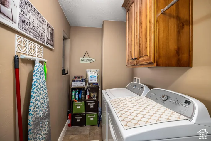 Laundry area featuring solid wood wall-mounted cabinetry, tile flooring, and wall-mounted storage hardware
