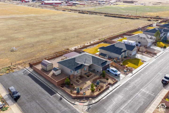 Corner lot residence featuring a landscaped yard with xeriscaping, stone exterior accents, an asphalt driveway, and two detached storage structures