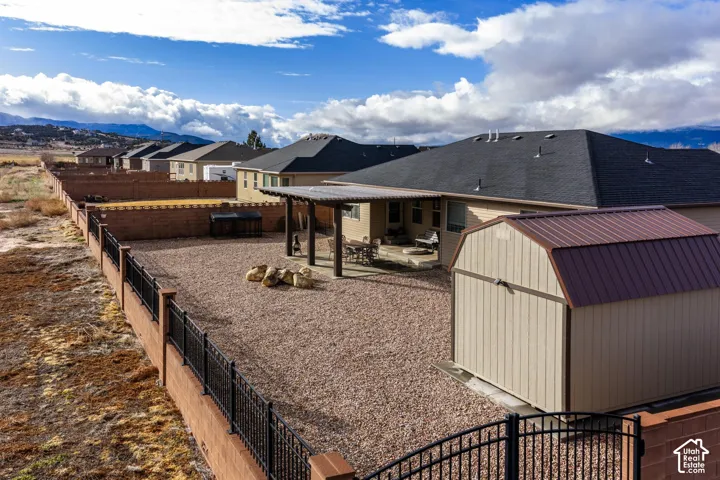 Backyard featuring a covered patio, detached storage shed, gravel landscaping, and a perimeter fence with a metal accent railing