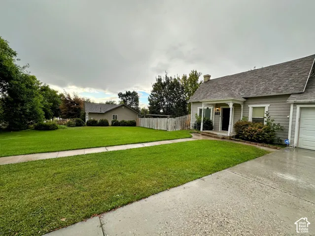 Exterior featuring horizontal siding, a covered entryway with decorative pillars, a concrete driveway, and an expansive lawn