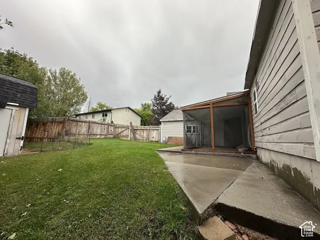 Backyard featuring a concrete patio, wood-frame screened-in porch, horizontal siding, and wood fencing
