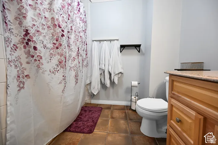 Bathroom featuring a wood-finish vanity with a stone-top counter, ceramic tile flooring, and a shower-tub combination with white wall tile
