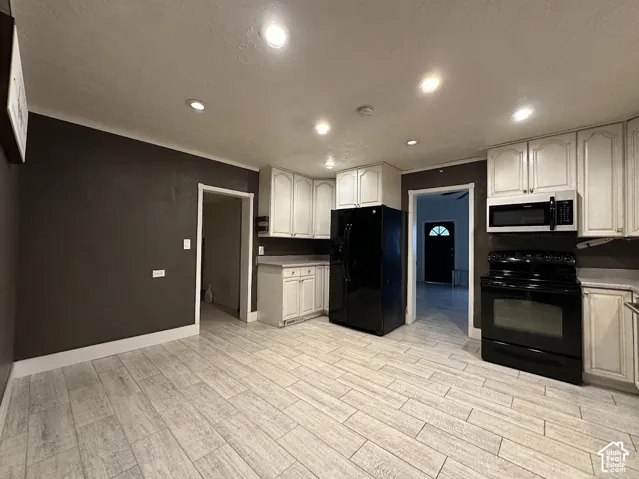 Kitchen featuring white cabinetry, wood-finish tile flooring, recessed ceiling lighting, and black appliances including a built-in microwave and range