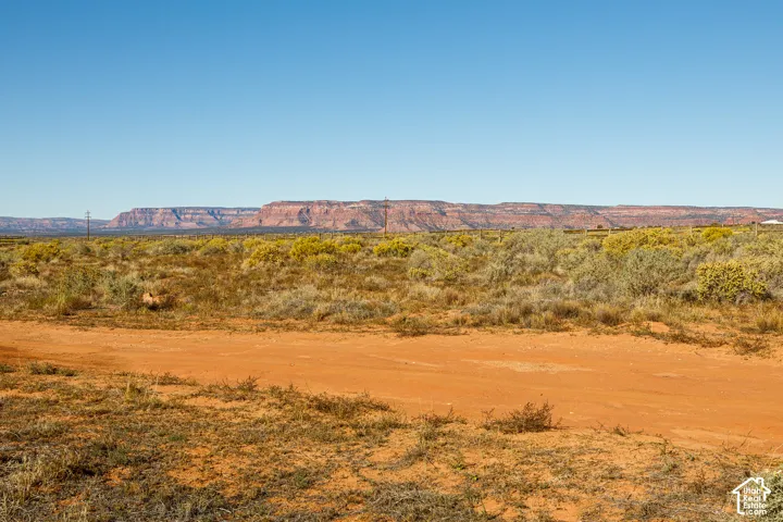 Expansive desert landscape featuring native brush, earthen terrain, and prominent mountain backdrops
