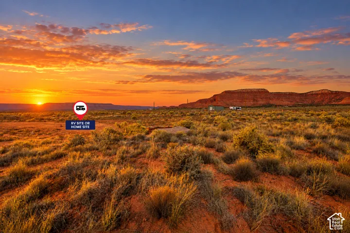 Expansive desert acreage featuring natural terrain, a dedicated site for a recreational vehicle or residence, and panoramic mountain scenery