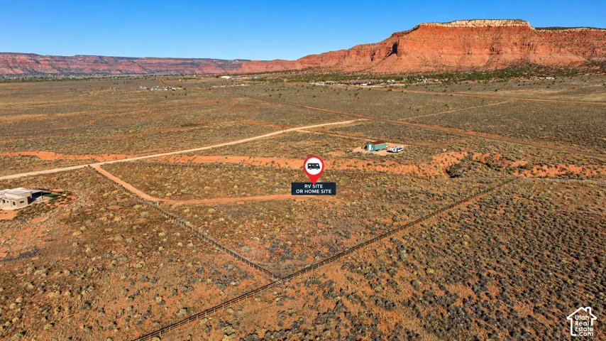 Expansive desert acreage featuring wire fencing, dirt access roads, and prominent rock formations