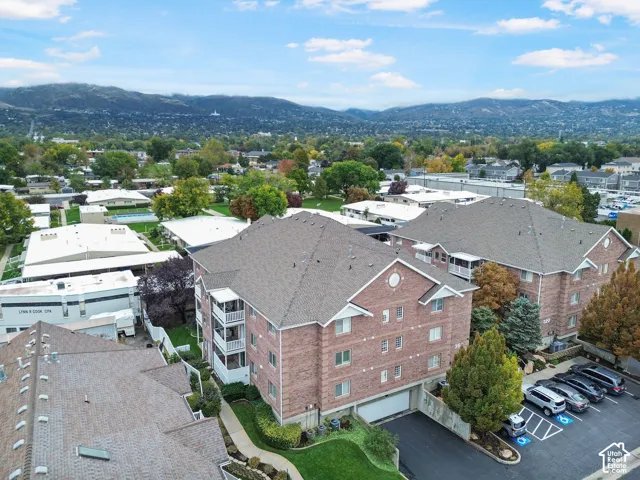 Multi-story brick exterior featuring integrated parking, private balconies, and asphalt shingle roofing, set against a mountain backdrop